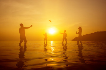 Silhouette of people playing at the beach in sunset