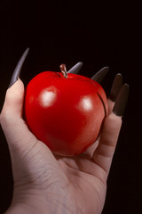 Apple in the hands with claws