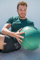 Gym workout with medicine ball exercise man doing russian twist exercises. Athlete working out doing exercises training oblique abs muscles on fitness centre floor.