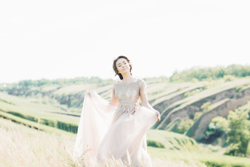 Fototapeta na wymiar fine art wedding photography. Beautiful bride with bouquet and dress with train in nature