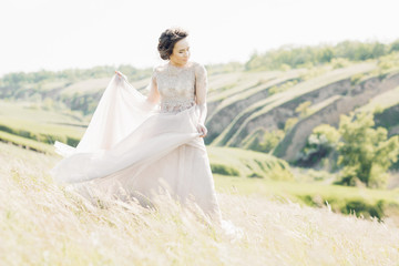 Fototapeta na wymiar fine art wedding photography. Beautiful bride with bouquet and dress with train in nature