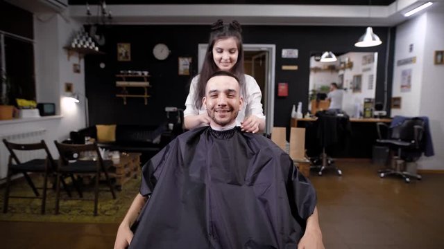 A happy man received his hairstyle in a beauty salon, a hairdresser completed the haircut and hair styling of a Babrenshop visitor