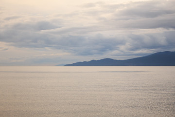 Photo of cloudy beach with mountain on the horizon
