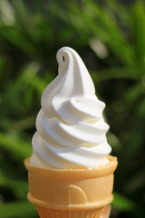 Vanilla soft serve ice cream cone in the sunlight, vertical photo 