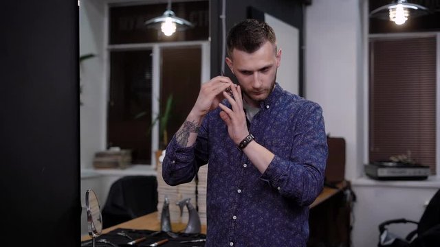 A professional hair stylist who works in barbershop holds scissors for cutting hair, a man twists a sharp object in his hands