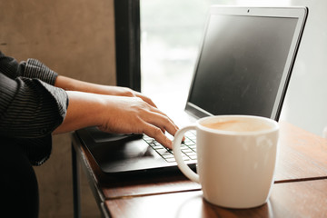 hand of business man typing on keyboard computer notebook. coffee cup putting beside laptop on wooden table. image for technology,workplace,computer,work,business concept