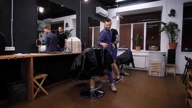A free and active hairdresser talks to a client of barbershop, a man wants to find out what hairstyle the client of the salon is waiting for