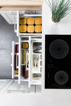 Top view of organized kitchen drawers and electric kitchen stove. Modern kitchen organization of spaces.