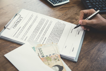 Obraz premium Businessman signing contract with money, South Korean won banknotes, on the table