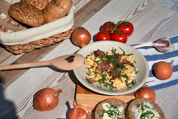 Čerstvá snídaně z domacích vajec, cibule a smažené šunky, prostřeno na dřevěném stole