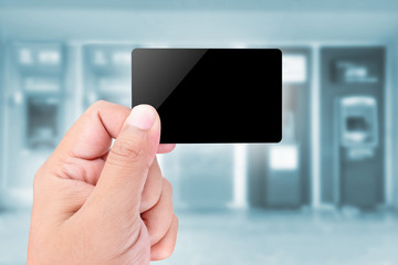 Credit Card held by hand on blurred abstract background of ATMs Machine