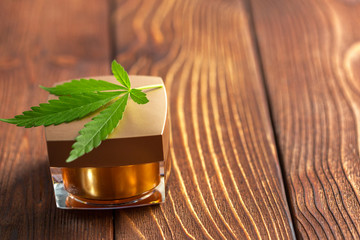 Cannabis leaves and oil on wooden background
