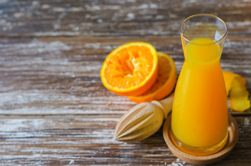 Freshly squeezed orange juice, organic squeezed oranges fruit  and  wooden citrus juicer on dark wooden table.Space for text.