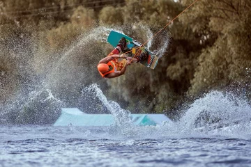 Fotobehang Man makes an extreme jump on wakeboarding, around there are a lot of splashes and splashes of water. This is an extreme sport. © Petro