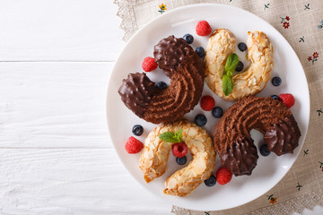 Almond and chocolate cookies in the shape of a horseshoe with fresh berries close-up. Horizontal top view