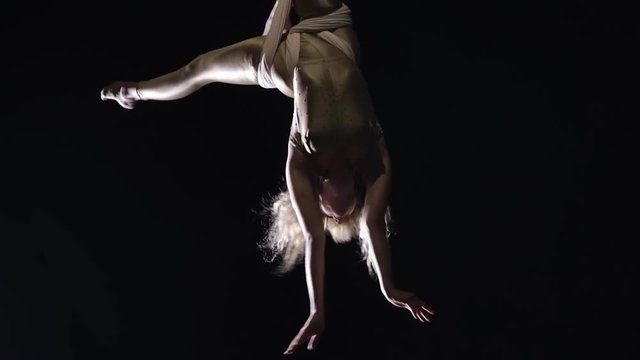 Woman aerial gymnast performing on silk in circus stage. Exciting acrobatic show.