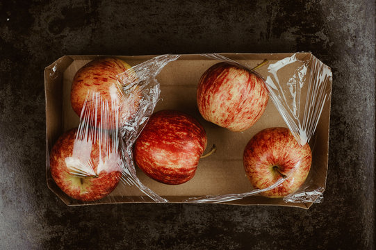 Apple wrapped in plastic. Excessive supermarkets packaging concept.