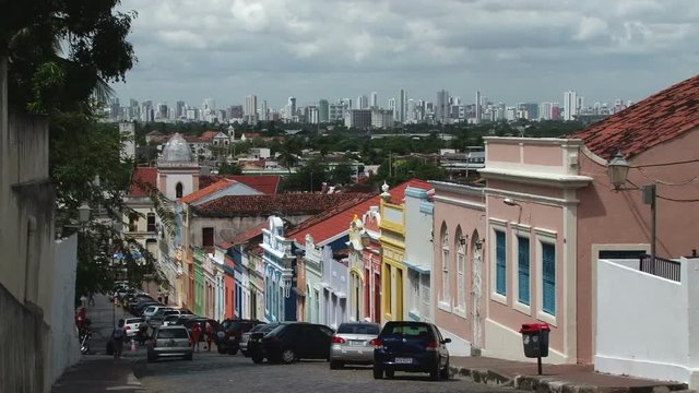 Colourful street of old historic centre in Olinda, Brazil. On the background new buildings of Recife