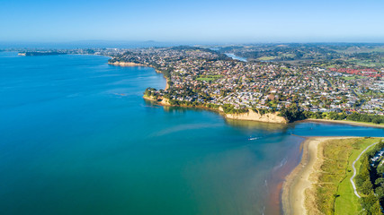 Naklejka na ściany i meble Aerial view on sunny beach with residential suburb on the background. Auckland, New Zealand.