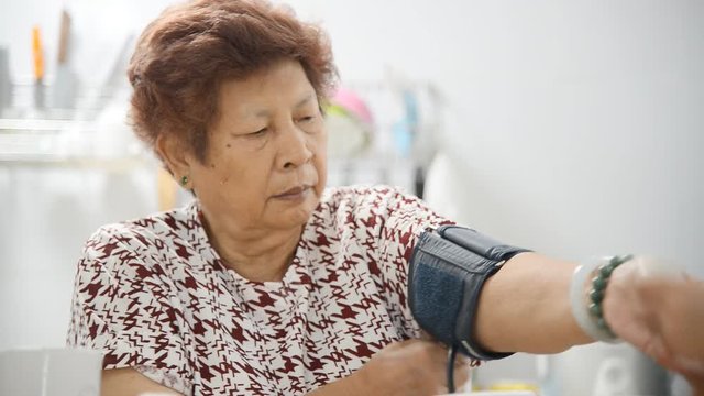 Asian senior woman making blood measuring herself 
