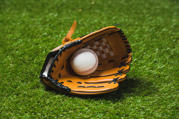 close up of professional baseball glove with ball on green grass