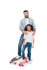 Happy father and daughter standing with skateboards and smiling at camera