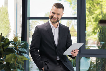 Fototapeta premium portrait of cheerful businessman with digital tablet in hands looking at camera