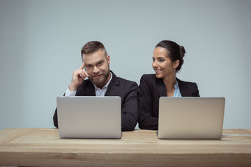 portrait of cheerful colleagues using laptops on workplace in office