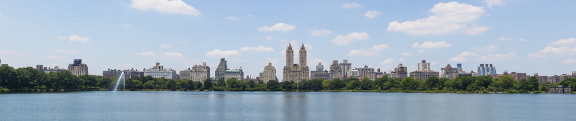 Fototapeta na wymiar High resolution panorama of Central Park West skyline and the Jacqueline Kennedy Reservoir in New York City with apartment skyscrapers over lake with fountain in midtown Manhattan and lake reflection