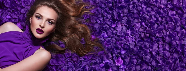 Foto op Aluminium Schoonheidssalon The girl in the petals. Beautiful young girl lies in the violet petals in a long dress. Glamor, luxe. Hair - curls. Makeup - arrows, purple lipstick. Love, romance.