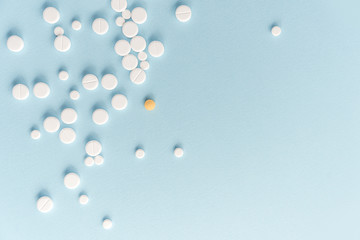 Top view of white pills with yellow tablet