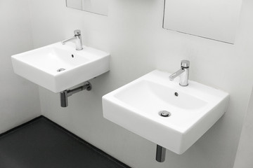 Fototapeta na wymiar Two washbasin to European public toilet, Two modern ceramic washbasins, Ceramic sink with chrome mixer in contemporary washroom, Modern european washbasin, Modern minimalist washstand