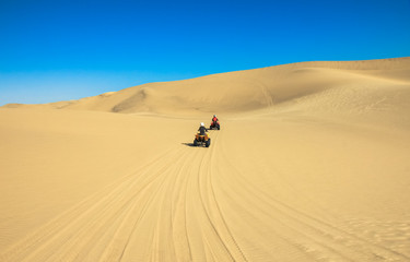 Fototapeta na wymiar Quad driving people - two happy bikers in sand desert.