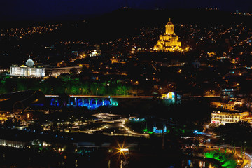 Night panorama view of Tbilisi, capital of Georgia country. Holy Trinity Cathedral (Sameba) and Presidential Administration at night with illumination and moving cars.