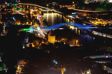 Fototapeta na wymiar Night aerial view on illuminated Bridge of Peace over Kura river. Famous landmark in Tbilisi, Georgia.