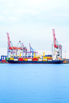 Container ship in the sea port. Port crane loads a container on a ship. Cargo transportation by sea.