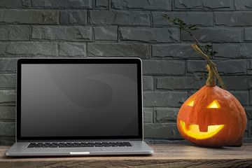 Laptop and halloween pumpkin head jack on old wooden table