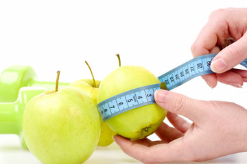 Cyan blue measuring tape in female hands wrapped around apple