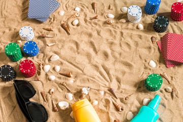 Gambling on vacation concept - white sand with seashells , colored poker chips and cards. Top view