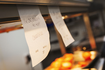 Close up of handwritten order tabs in a restaurant kitchen.