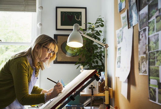 Woman standing at a drawing board, drawing with a fineliner.
