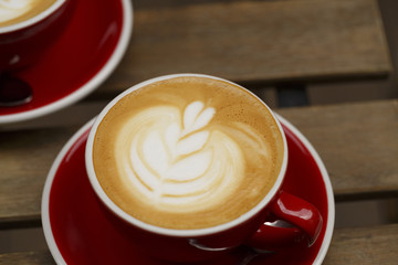 Coffee in red cup on wooden table, Colorful photo of coffee with defocused table in the background, Selective focus with shallow depth of field