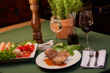 Rouladen Rinderlouladen serviert auf weißem Teller mit Soße und Wein und Wasser Glas