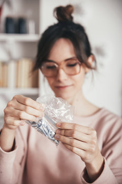Woman looking at plastic bag with tools and screws for assembling furniture