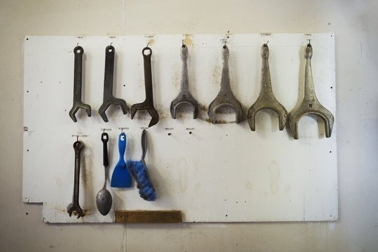 Close up of metal hand tools hanging on a wall in a brewery.