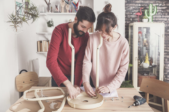 Young couple assembling flat-pack stool at home