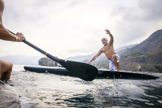 Mexico, Banderas Bay, Los Arcos National Marine Park, man falling from paddleboard