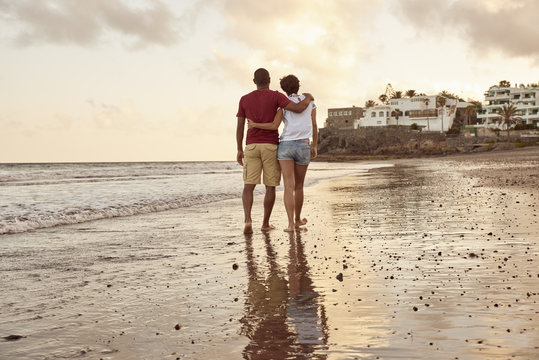 Spain, Canary Islands, Gran Canaria, back view of couple in love walking on the beach