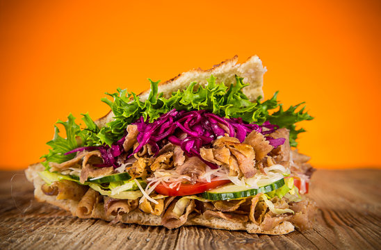 Close up of kebab sandwich on old wooden table.