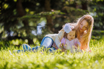 Family, mother and baby girl resting on nature, lying on grass
